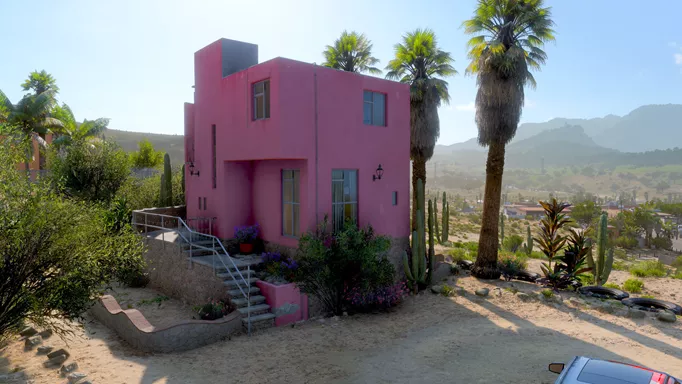 A pink house surrounds by palm trees.